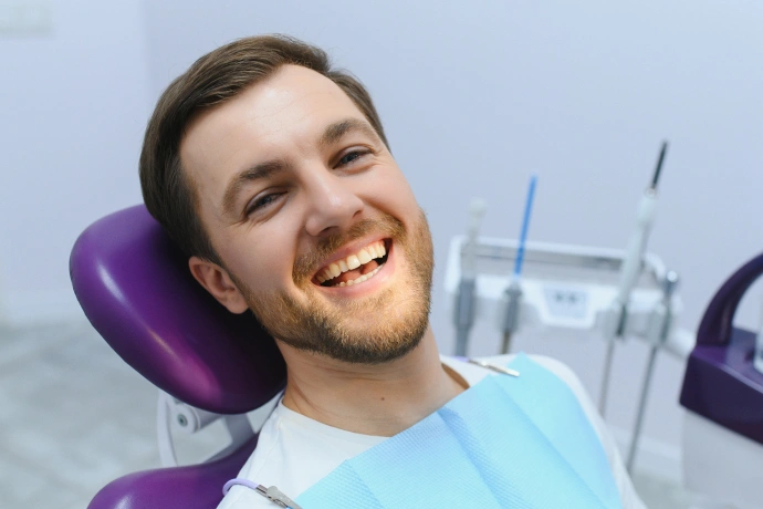 Smiling male patient in dental chair at Bartlesville Dental Studio with dentist office visible in background.