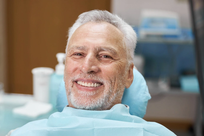 Smiling male patient in dental bib at Bartlesville Dental Studio treatment chair.