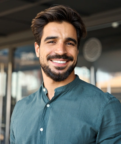 Smiling man in blue shirt at modern dental office, professional headshot portrait.