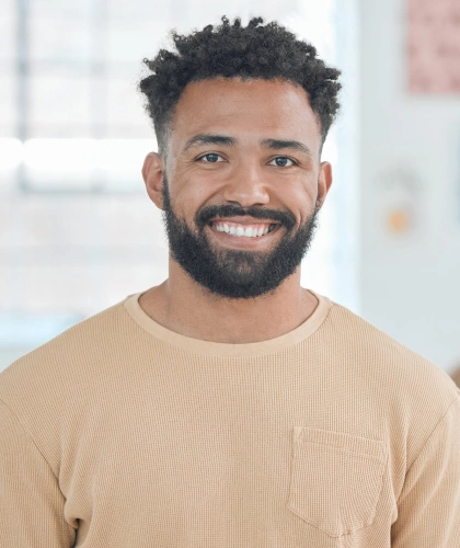 Smiling man in beige shirt, professional headshot in dental office setting.
