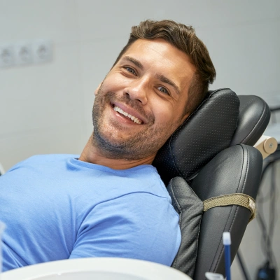 Man smiling in dental chair wearing blue shirt at Bartlesville Dental Studio