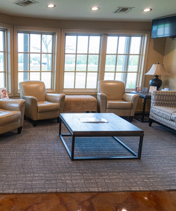 Comfortable dental office waiting room with chairs, coffee table, and large windows.